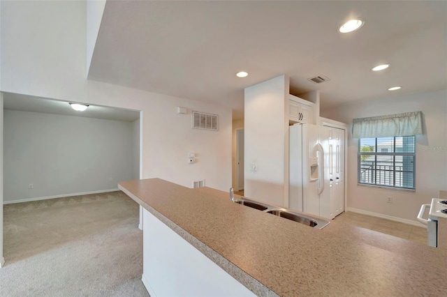 kitchen featuring white fridge with ice dispenser, white cabinetry, light carpet, and sink