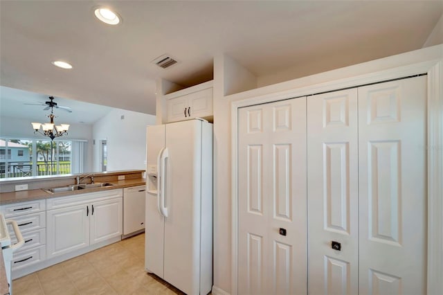 kitchen featuring white appliances, sink, ceiling fan with notable chandelier, pendant lighting, and white cabinets