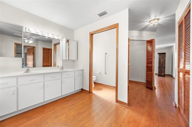 bathroom featuring toilet, hardwood / wood-style floors, vanity, and ceiling fan