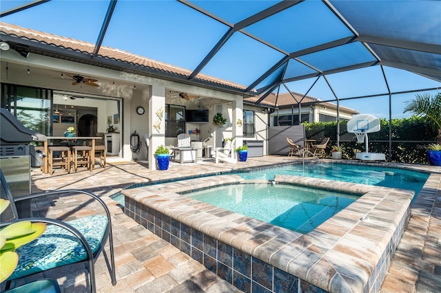 view of swimming pool featuring an outdoor bar, ceiling fan, glass enclosure, a patio area, and an in ground hot tub