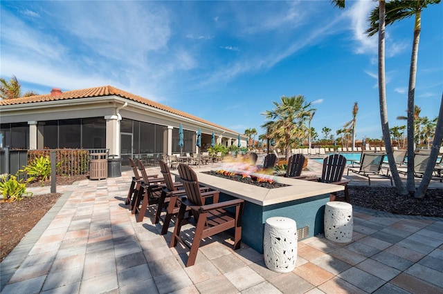 view of patio with a sunroom and an outdoor fire pit