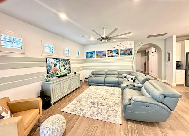 living room with arched walkways, ceiling fan, visible vents, and light wood-style floors