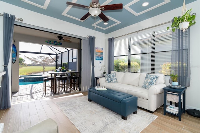 living room with a sunroom, ceiling fan, and wood finished floors