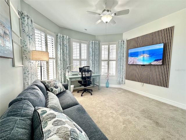 carpeted office with baseboards and a ceiling fan