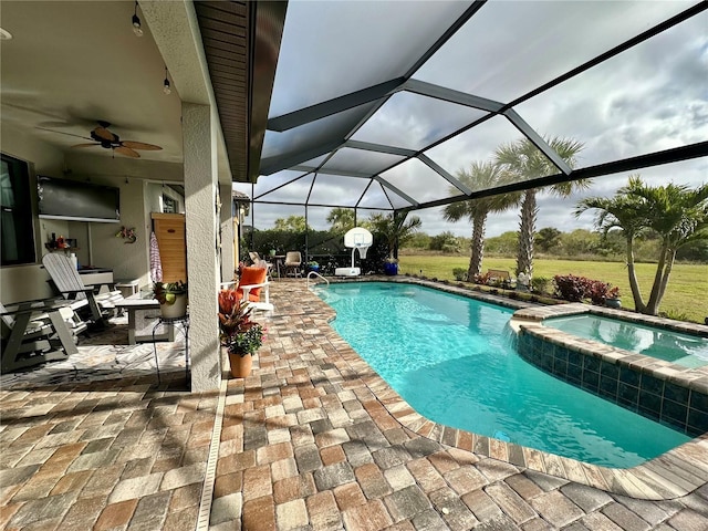 view of pool featuring glass enclosure, a pool with connected hot tub, a ceiling fan, and a patio