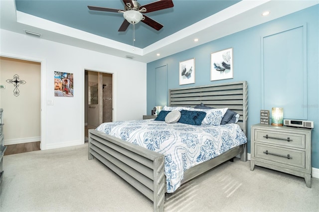 bedroom with recessed lighting, light carpet, visible vents, baseboards, and a tray ceiling