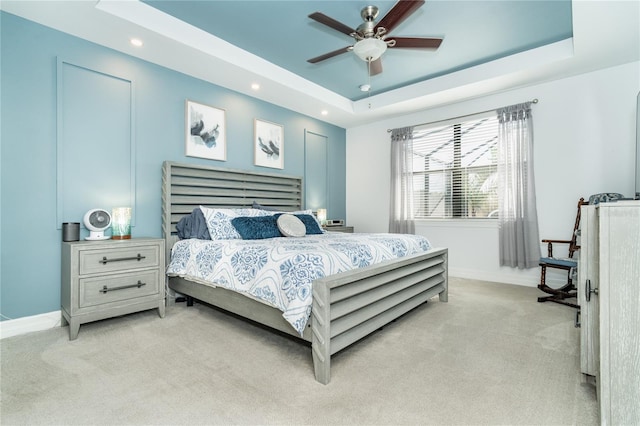 bedroom with a tray ceiling, light colored carpet, baseboards, and recessed lighting