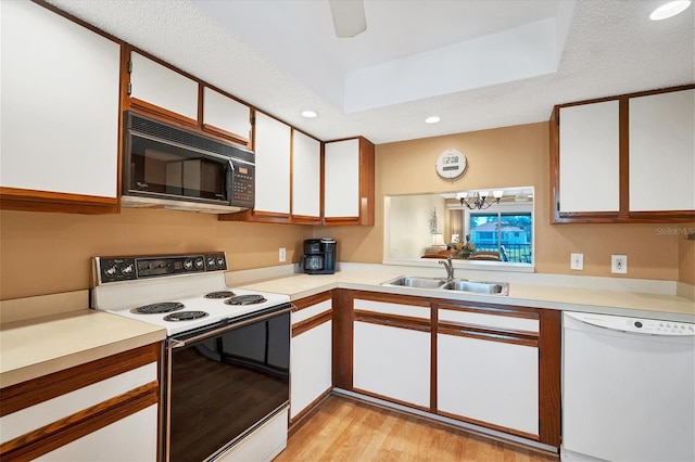 kitchen with white appliances, white cabinets, sink, light hardwood / wood-style flooring, and a textured ceiling