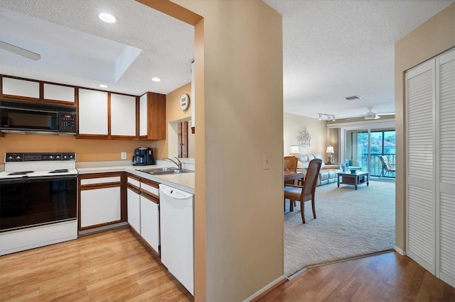 kitchen with sink, white appliances, a textured ceiling, and light hardwood / wood-style flooring