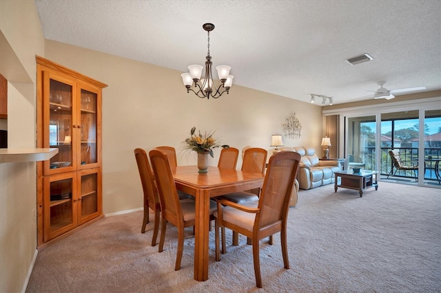 carpeted dining room with ceiling fan with notable chandelier and a textured ceiling