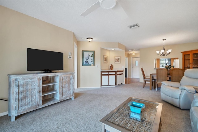 living room featuring a textured ceiling, ceiling fan with notable chandelier, and light carpet