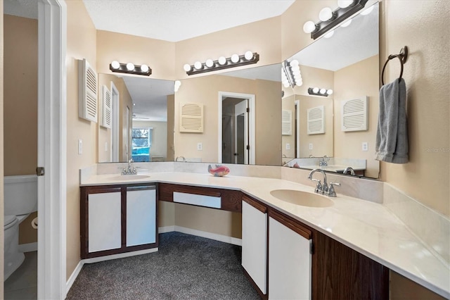 bathroom with a textured ceiling, vanity, and toilet