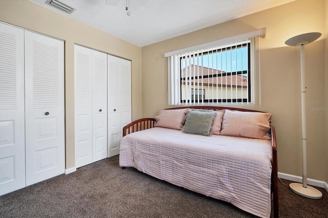 carpeted bedroom with a textured ceiling and two closets