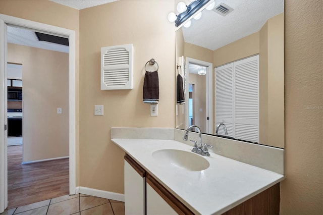 bathroom with tile patterned floors, vanity, and a textured ceiling