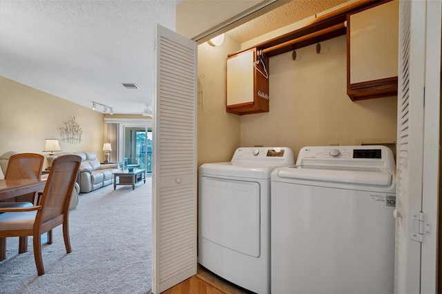 laundry room featuring cabinets, light carpet, a textured ceiling, and independent washer and dryer