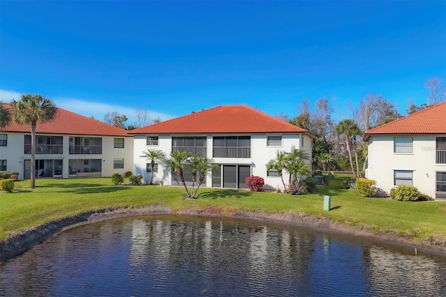 rear view of property featuring a lawn and a water view