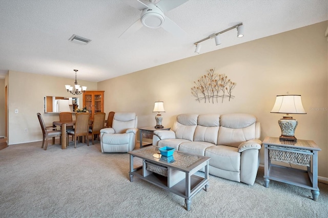 carpeted living room with a textured ceiling, ceiling fan with notable chandelier, and track lighting