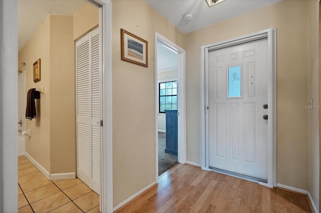 foyer entrance with a textured ceiling and light hardwood / wood-style flooring