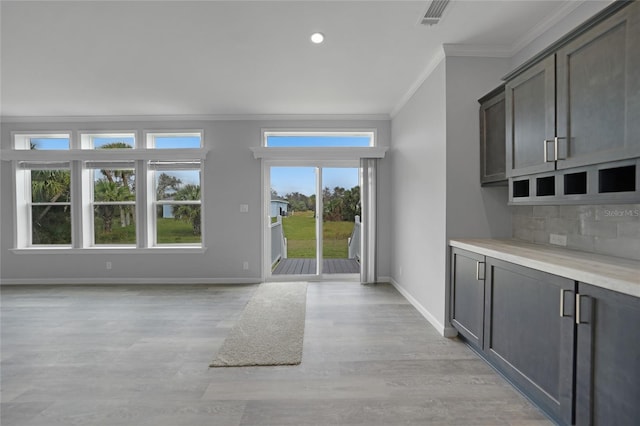19196 Raymond Ave, Port Charlotte, FL 33954 - kitchen with crown molding, baseboards, light wood-style floors, decorative backsplash, and light countertops