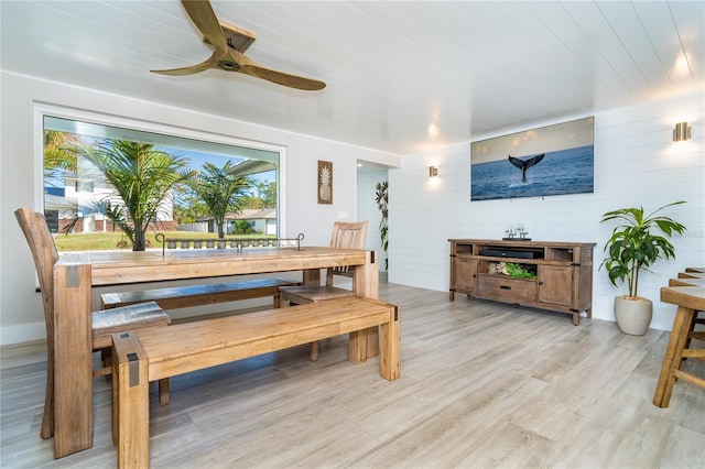 dining space featuring light hardwood / wood-style floors, wood walls, wooden ceiling, and ceiling fan