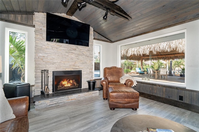 living room featuring vaulted ceiling with beams, hardwood / wood-style flooring, wooden ceiling, and a fireplace