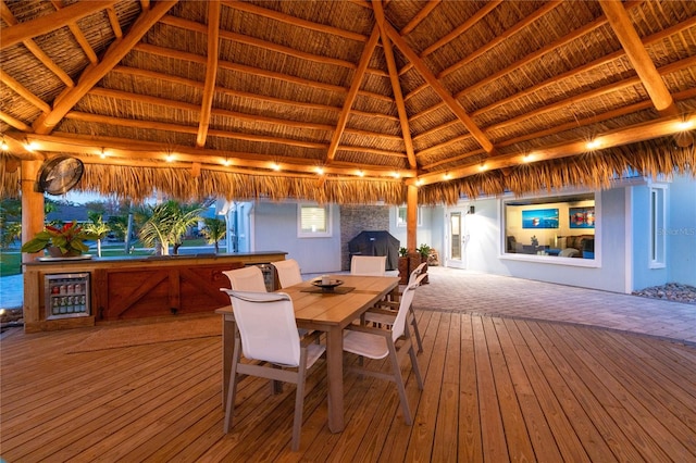 dining space featuring vaulted ceiling with beams, wine cooler, wood-type flooring, and a fireplace