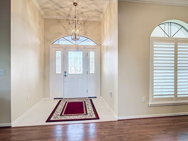 foyer featuring hardwood / wood-style flooring, ornamental molding, and a chandelier