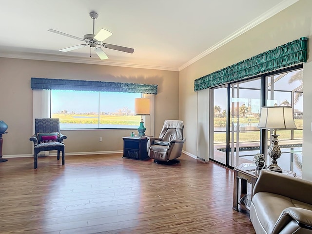 living area with crown molding, wood-type flooring, plenty of natural light, and ceiling fan