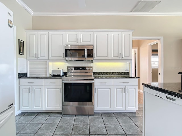 kitchen with decorative backsplash, appliances with stainless steel finishes, white cabinetry, dark stone countertops, and ornamental molding