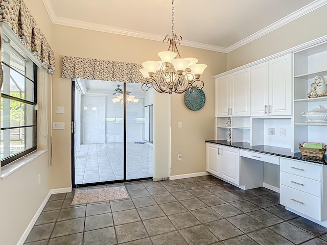 kitchen with dark tile patterned flooring, hanging light fixtures, ornamental molding, white cabinetry, and ceiling fan with notable chandelier