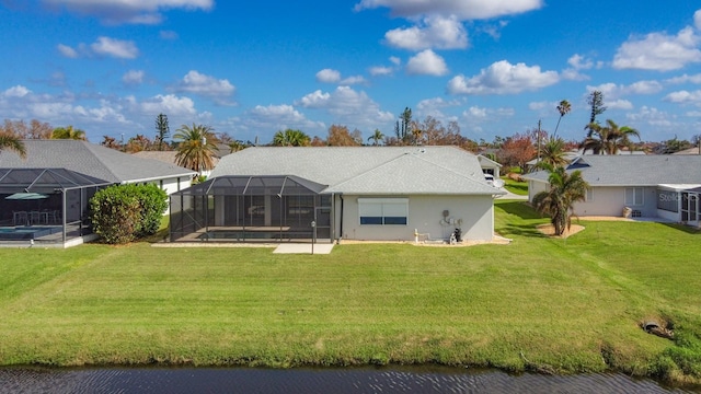 back of property with a pool, a water view, a lawn, a patio area, and glass enclosure