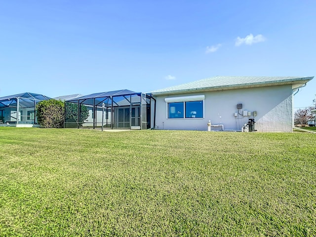 rear view of property featuring a yard and glass enclosure