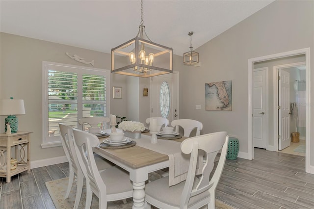 dining space featuring light hardwood / wood-style flooring, a notable chandelier, and vaulted ceiling