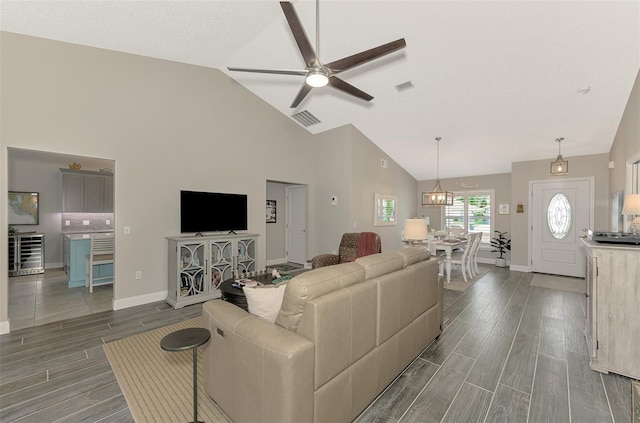 living room featuring dark wood-type flooring, high vaulted ceiling, and ceiling fan with notable chandelier