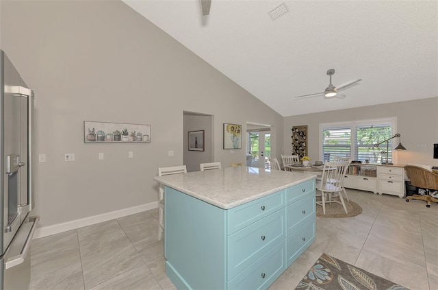 kitchen featuring a kitchen island, light tile patterned floors, blue cabinetry, high vaulted ceiling, and ceiling fan