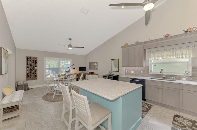 kitchen featuring decorative backsplash, a breakfast bar area, stainless steel dishwasher, sink, and a center island