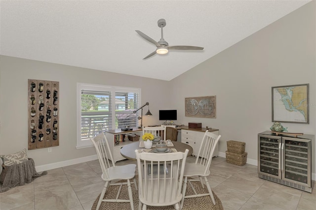 tiled dining space with ceiling fan, wine cooler, a textured ceiling, and lofted ceiling