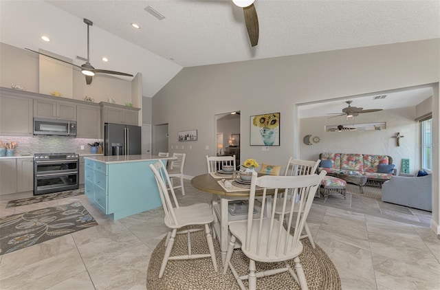 tiled dining area with a textured ceiling, high vaulted ceiling, and ceiling fan