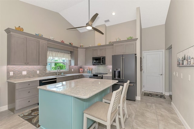 kitchen with a center island, ceiling fan, stainless steel appliances, high vaulted ceiling, and a breakfast bar