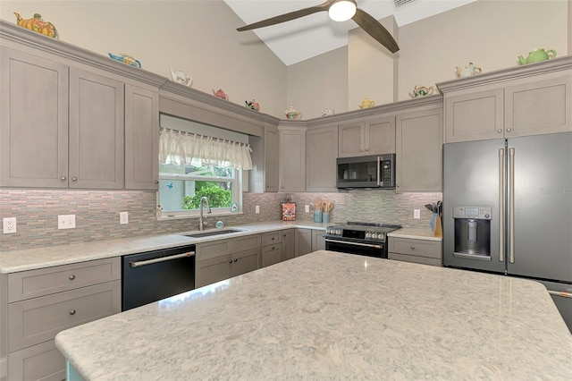 kitchen with tasteful backsplash, light stone counters, ceiling fan, sink, and stainless steel appliances