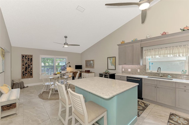 kitchen featuring sink, dishwasher, a kitchen island, a kitchen breakfast bar, and high vaulted ceiling