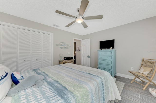 bedroom with a closet, ceiling fan, a textured ceiling, and light hardwood / wood-style floors