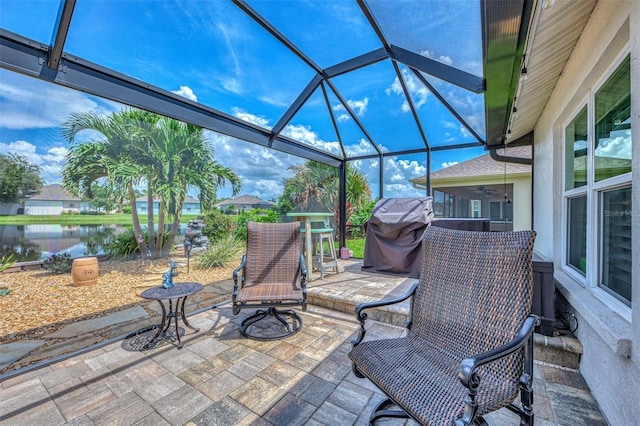 view of patio featuring grilling area, ceiling fan, a water view, and a lanai