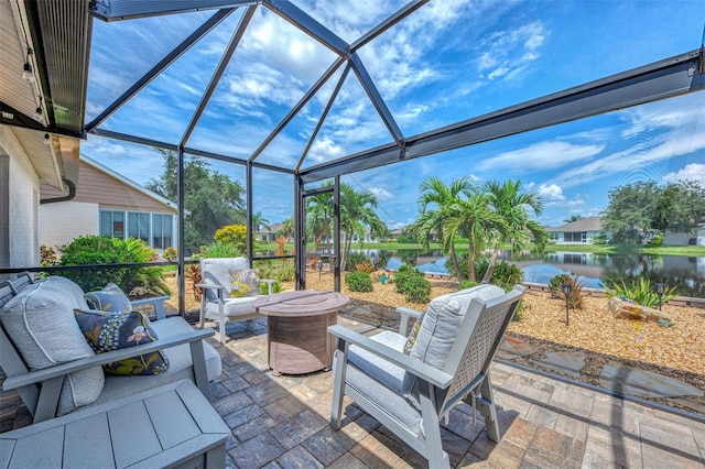 view of patio / terrace featuring a water view, glass enclosure, and a fire pit