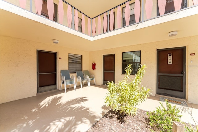 view of exterior entry with a patio and a balcony