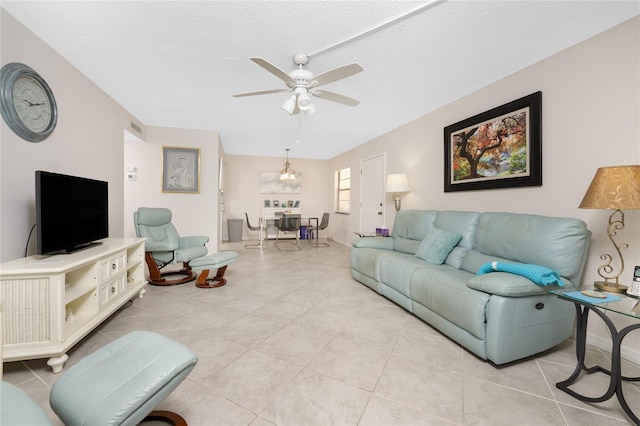 tiled living room featuring a textured ceiling and ceiling fan with notable chandelier