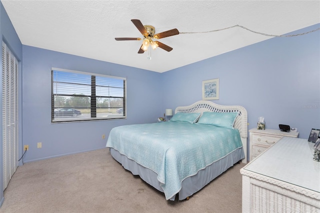 carpeted bedroom with ceiling fan and a textured ceiling