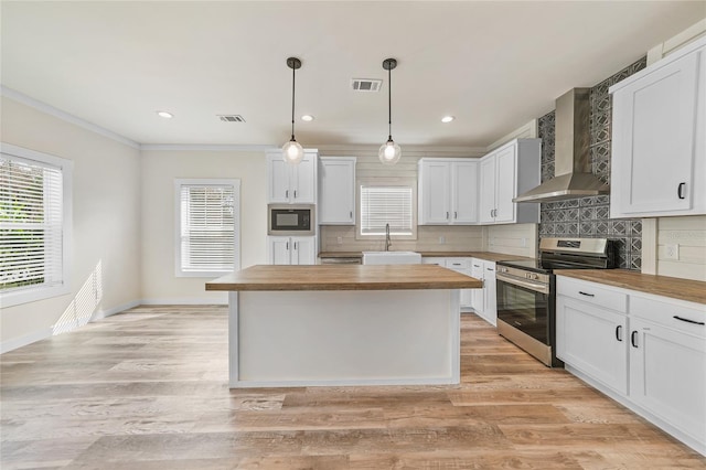 kitchen featuring wall chimney range hood, black microwave, white cabinetry, stainless steel stove, and wooden counters