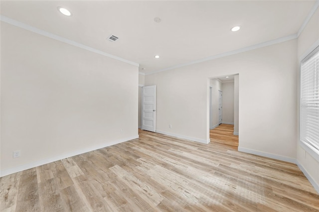 empty room with crown molding and light hardwood / wood-style floors