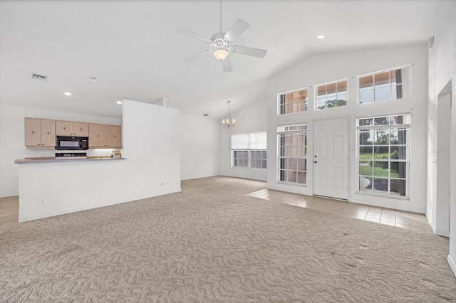 unfurnished living room featuring ceiling fan with notable chandelier, high vaulted ceiling, a wealth of natural light, and light colored carpet